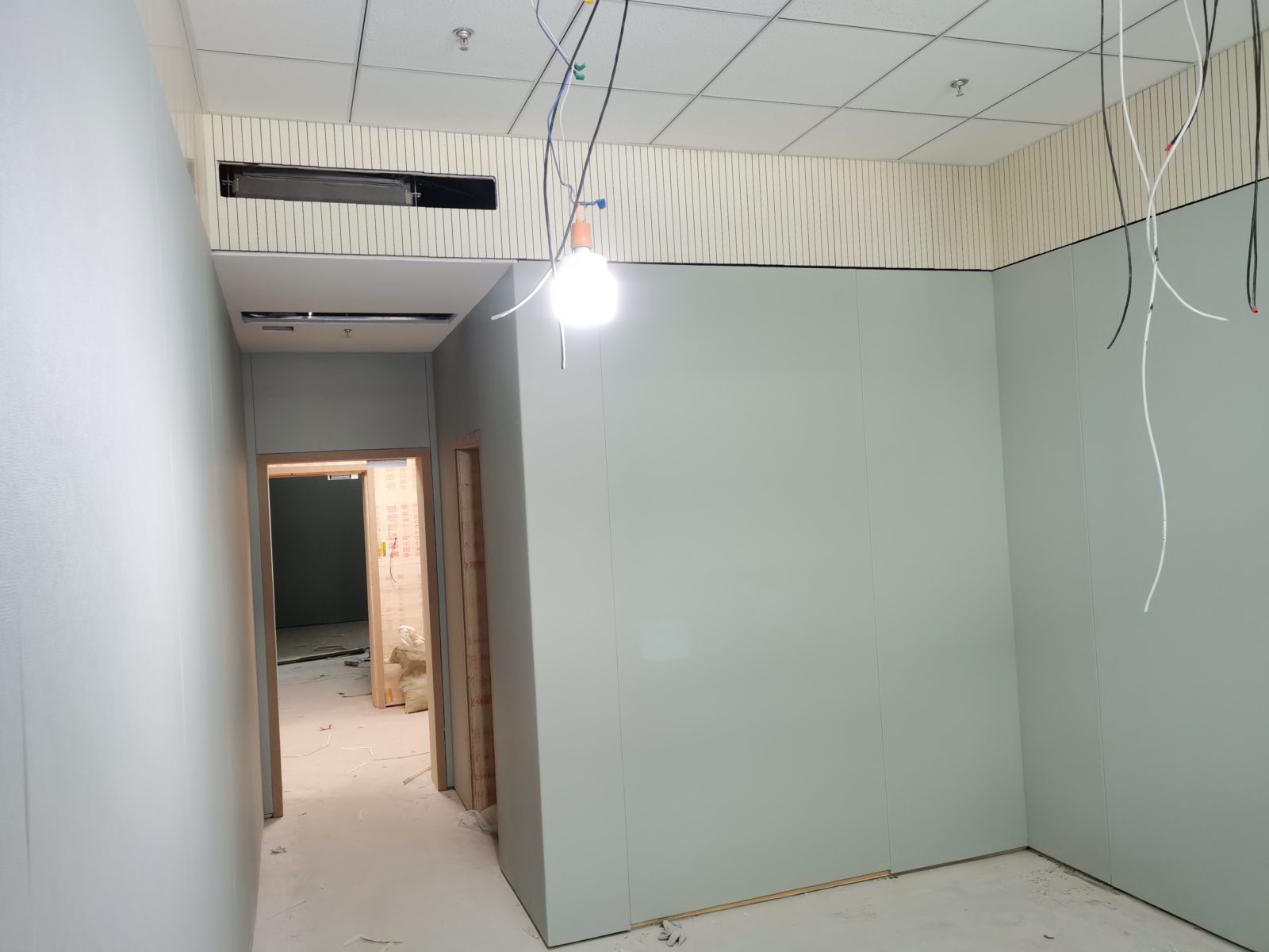 办案区审讯室防撞软包墙面安装实景,浅灰色软包板搭配上部木条吸音板,适用于公检法办案区防撞防自伤装修